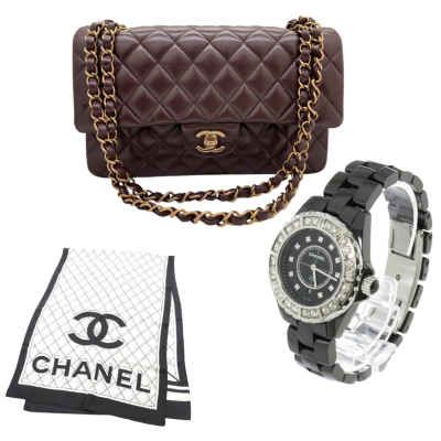 Luxury accessories: burgundy quilted Chanel handbag with a gold chain, a black jeweled Chanel watch, and a Chanel dust bag.